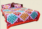 Colorful floral-patterned applique bedspread on a bed with matching pillows.