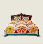 Colorful floral applique bedsheet on a bed with wooden headboard