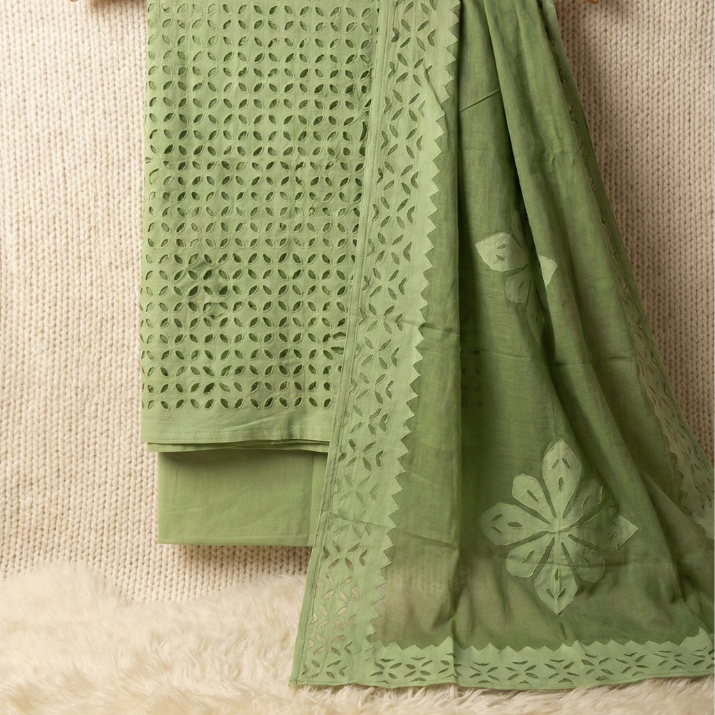 Green applique suit fabrics with intricate cut-out patterns on a textured surface