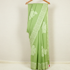 Green applique saree with floral cutwork patterns on a hanger against a white background