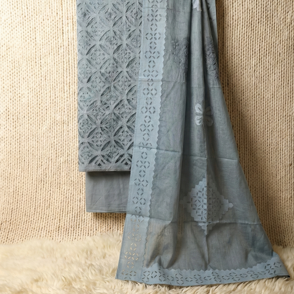 Gray applique dress material fabric set with intricate lace patterns draped over a textured beige surface