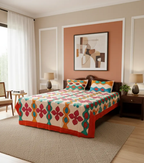 Bedroom with a colorful applique bedsheet on a bed, framed artwork on the wall, and side tables.