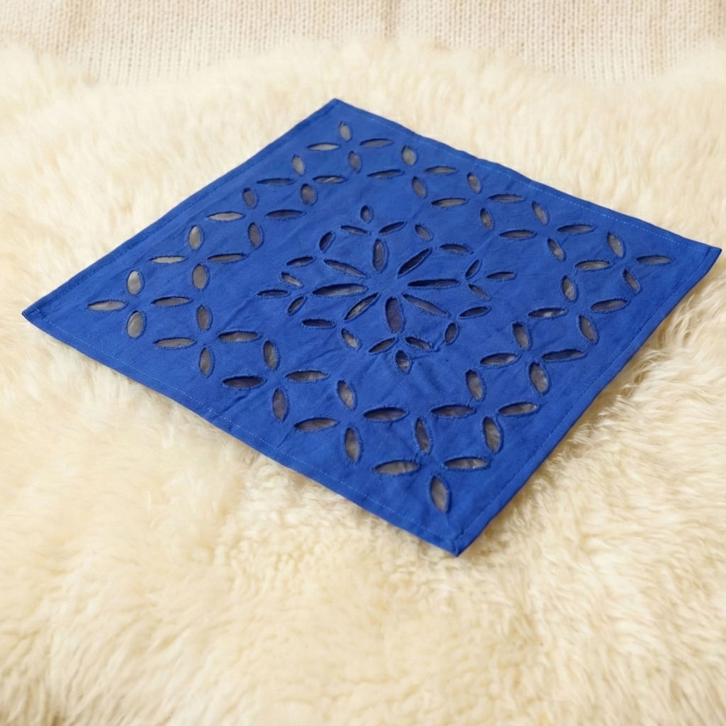 Blue decorative table linen with floral cutout pattern on a beige surface