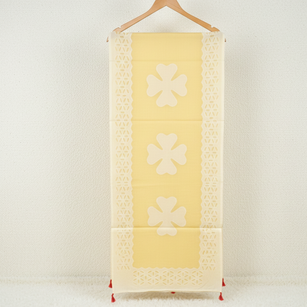 Yellow applique saree with floral patterns on a wooden hanger against a white background
